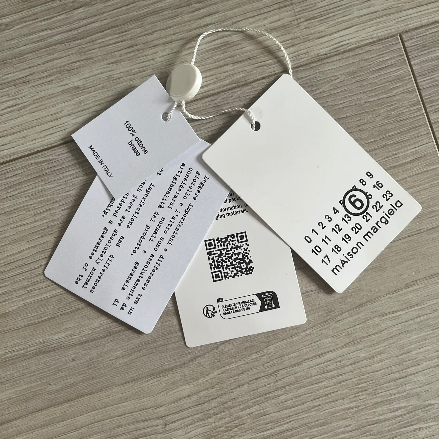 Clothing tags with text and a QR code on a wooden surface