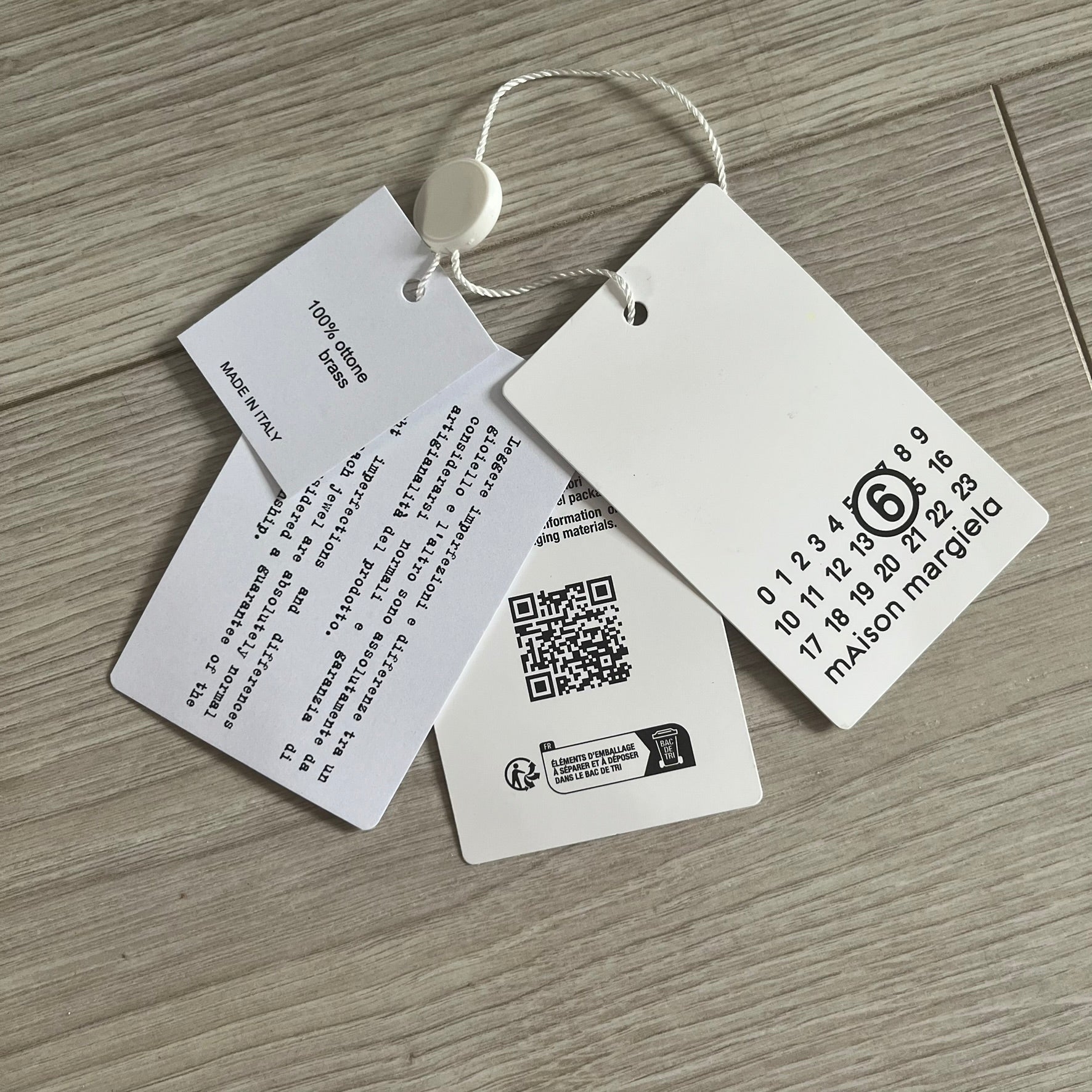 Clothing tags with text and a QR code on a wooden surface