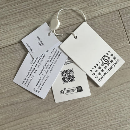 Clothing tags with text and a QR code on a wooden surface
