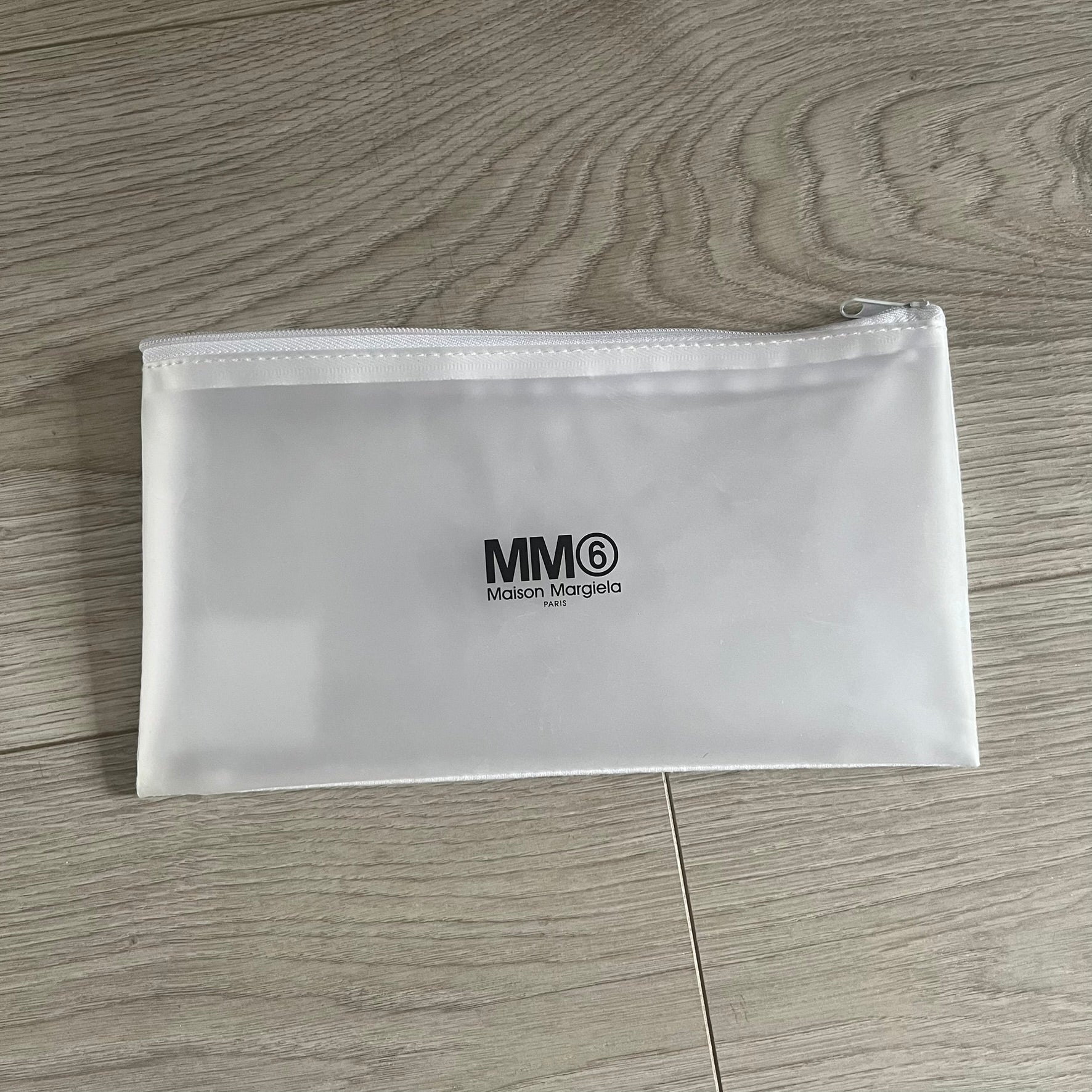 Clear pouch with MM6 Maison Margiela logo on a wooden surface