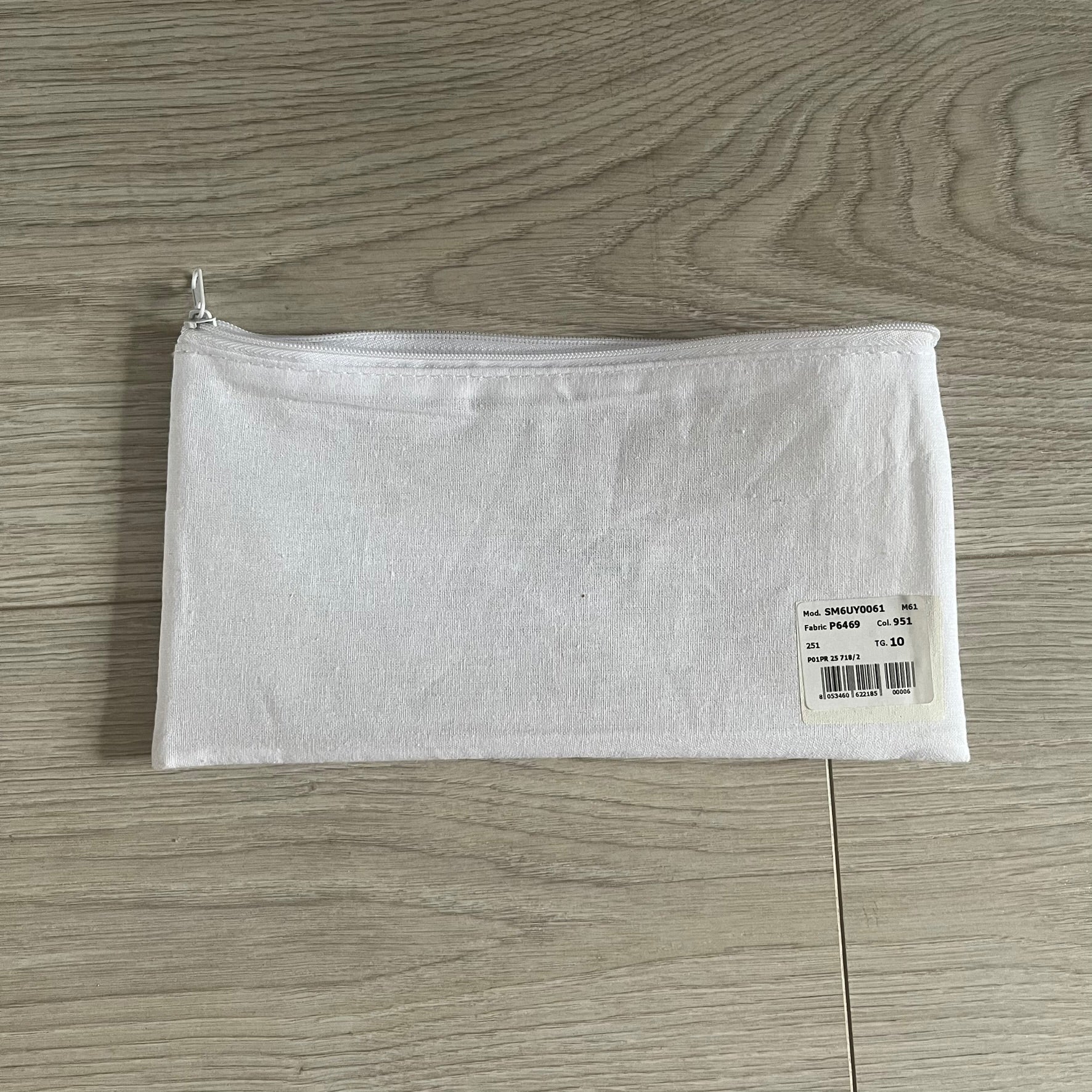 White zippered pouch with a label on a wooden surface