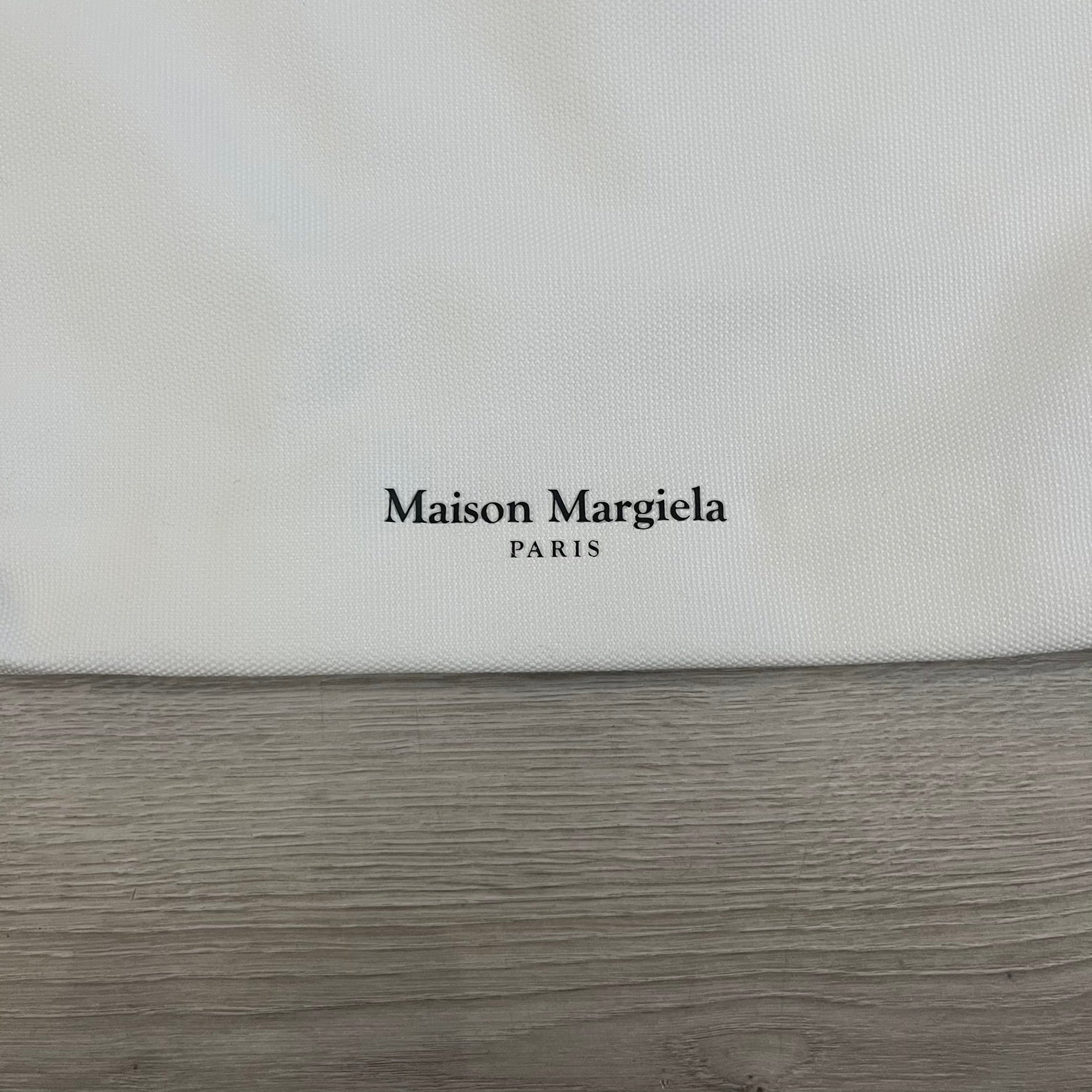 Maison Margiela Replica Tote Bag in off-white with a textured finish inspired by natural jute. Features “Replica” fragrances patch on one side, an interior slip pocket, and small “Maison Margiela Paris” text on the other side. Made in Paris, versatile for daily errands, work, or casual outings.