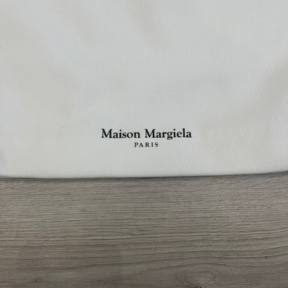 Maison Margiela Replica Tote Bag in off-white with a textured finish inspired by natural jute. Features “Replica” fragrances patch on one side, an interior slip pocket, and small “Maison Margiela Paris” text on the other side. Made in Paris, versatile for daily errands, work, or casual outings.