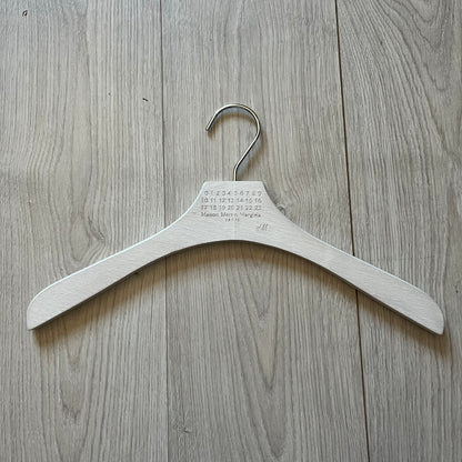 Maison Margiela x H&amp;M 2012 clothing hanger in a white-washed wood finish. Features a carved Margiela and H&amp;M logo with a clean, classic silhouette. Ideal for displaying tees, hoodies, or jackets with a touch of designer minimalism.