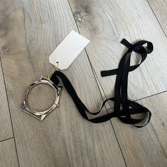 Maison Margiela x H&amp;M AW09 Enlarged Watch Frame Bracelet is a stainless steel bracelet from the 2012 collaboration between Maison Margiela and H&amp;M, based on an original Autumn/Winter 2009 design. The piece is shaped like an oversized watch case but functions as a bracelet, featuring a side clasp opening mechanism. It includes engraved tonal branding on the interior and can also be worn as a pendant. Made in Italy, it comes with the original tag.