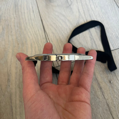 Maison Margiela x H&amp;M AW09 Enlarged Watch Frame Bracelet is a stainless steel bracelet from the 2012 collaboration between Maison Margiela and H&amp;M, based on an original Autumn/Winter 2009 design. The piece is shaped like an oversized watch case but functions as a bracelet, featuring a side clasp opening mechanism. It includes engraved tonal branding on the interior and can also be worn as a pendant. Made in Italy, it comes with the original box, dustbag, and tags.