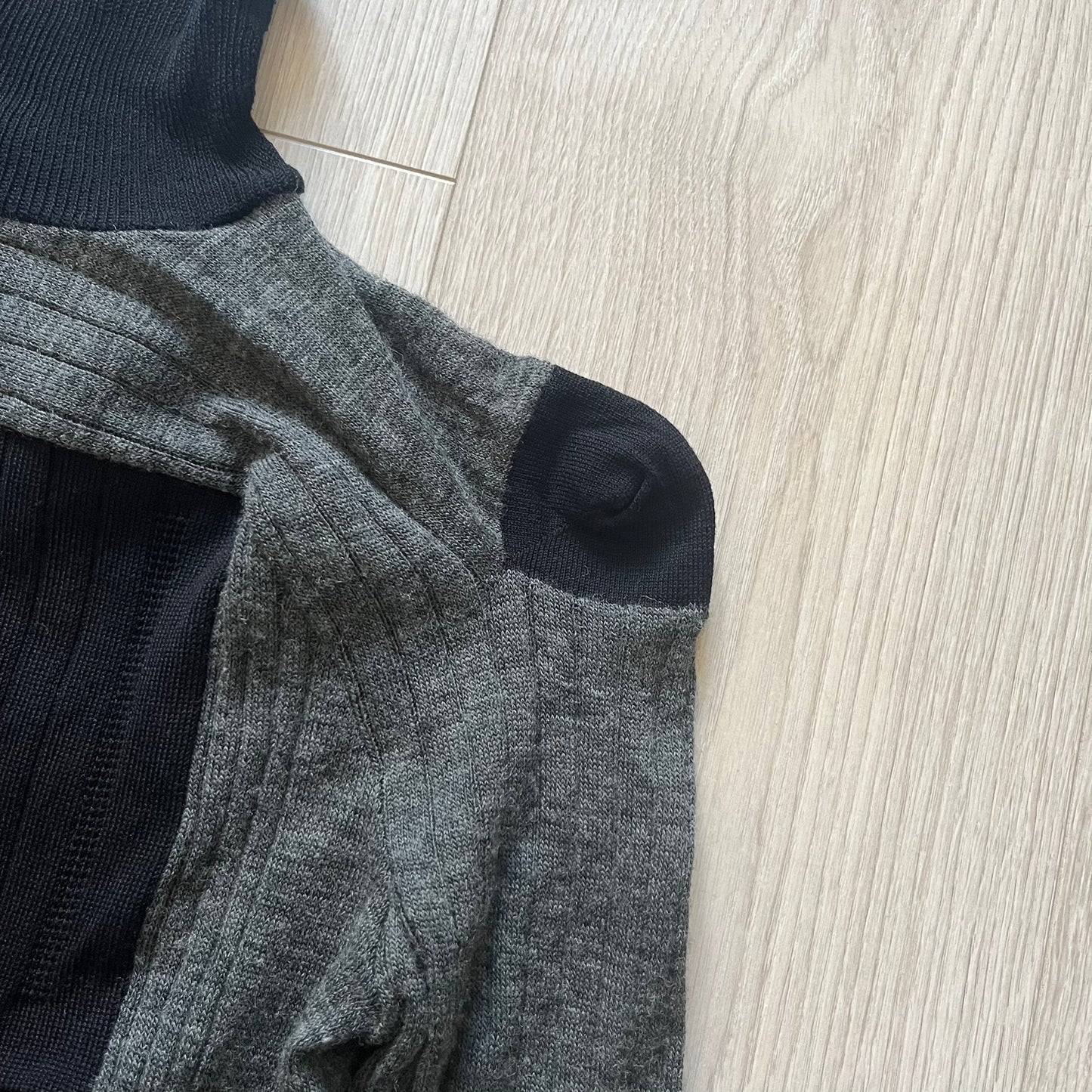 Maison Margiela x H&amp;M AW12 wool sweater in gray and black, designed with stretch fabric for a snug, comfortable fit. Features sock-inspired panels with heel details on the shoulders and elbows, a turtleneck, and long sleeves. A standout piece from the 2012 collaboration, inspired by Margiela’s Fall 1989 collection.