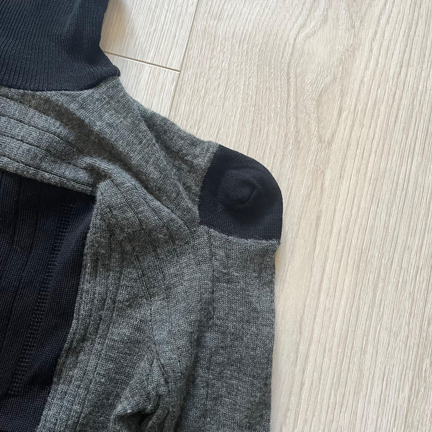 Maison Margiela x H&amp;M AW12 wool sweater in gray and black, designed with stretch fabric for a snug, comfortable fit. Features sock-inspired panels with heel details on the shoulders and elbows, a turtleneck, and long sleeves. A standout piece from the 2012 collaboration, inspired by Margiela’s Fall 1989 collection.