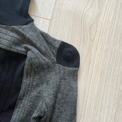 Maison Margiela x H&amp;M AW12 wool sweater in gray and black, designed with stretch fabric for a snug, comfortable fit. Features sock-inspired panels with heel details on the shoulders and elbows, a turtleneck, and long sleeves. A standout piece from the 2012 collaboration, inspired by Margiela’s Fall 1989 collection.