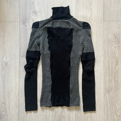 Maison Margiela x H&amp;M AW12 wool sweater in gray and black, designed with stretch fabric for a snug, comfortable fit. Features sock-inspired panels with heel details on the shoulders and elbows, a turtleneck, and long sleeves. A standout piece from the 2012 collaboration, inspired by Margiela’s Fall 1989 collection.