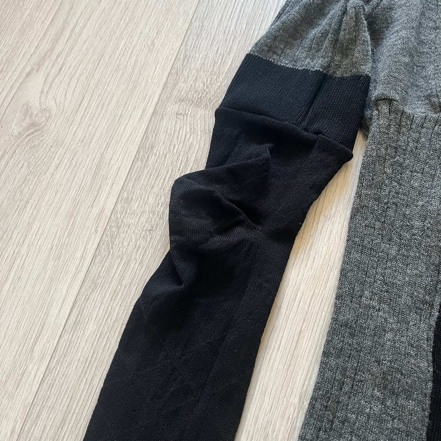 Maison Margiela x H&amp;M AW12 wool sweater in gray and black, designed with stretch fabric for a snug, comfortable fit. Features sock-inspired panels with heel details on the shoulders and elbows, a turtleneck, and long sleeves. A standout piece from the 2012 collaboration, inspired by Margiela’s Fall 1989 collection.