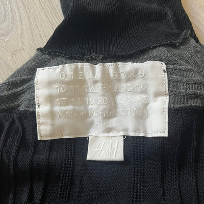 Maison Margiela x H&amp;M AW12 wool sweater in gray and black, designed with stretch fabric for a snug, comfortable fit. Features sock-inspired panels with heel details on the shoulders and elbows, a turtleneck, and long sleeves. A standout piece from the 2012 collaboration, inspired by Margiela’s Fall 1989 collection.
