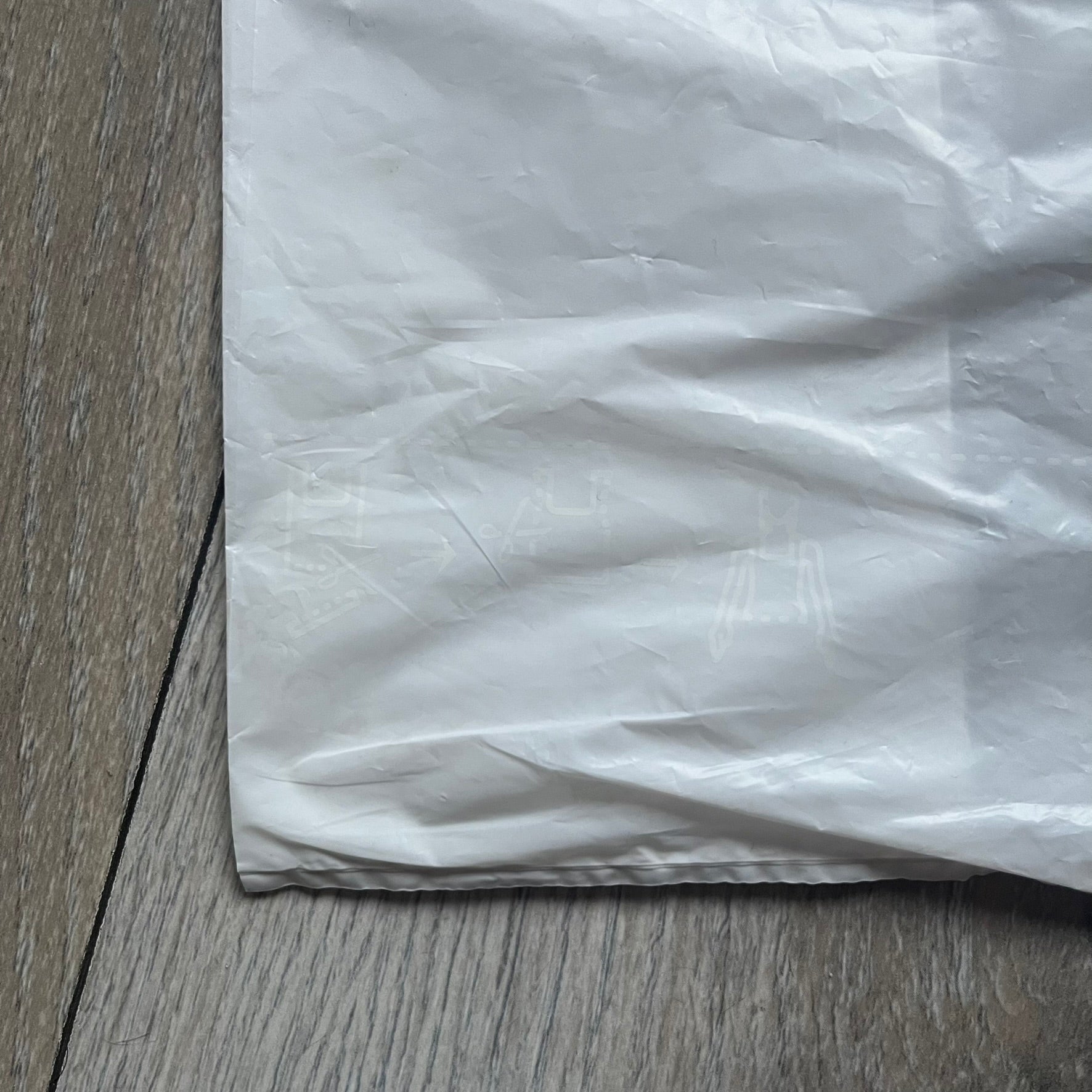 Clear/white plastic bag from the Maison Margiela x H&amp;M collaboration, designed with a cut-off bottom that allows it to be worn as a top or tank. Features big Maison Margiela x H&amp;M logos printed on the front, visible through the semi-transparent material.