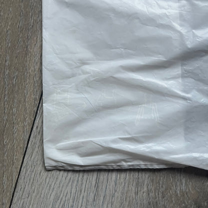 Clear/white plastic bag from the Maison Margiela x H&amp;M collaboration, designed with a cut-off bottom that allows it to be worn as a top or tank. Features big Maison Margiela x H&amp;M logos printed on the front, visible through the semi-transparent material.