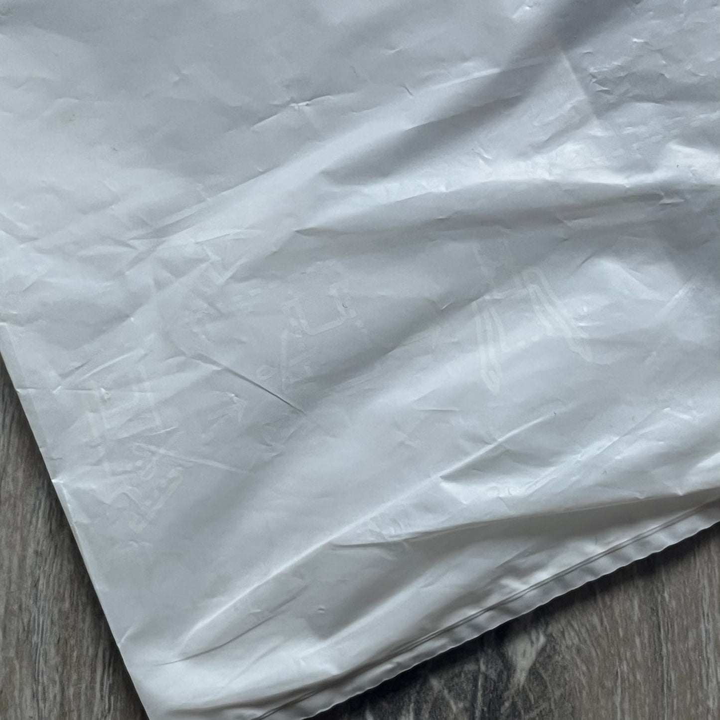 Clear/white plastic bag from the Maison Margiela x H&amp;M collaboration, designed with a cut-off bottom that allows it to be worn as a top or tank. Features big Maison Margiela x H&amp;M logos printed on the front, visible through the semi-transparent material.