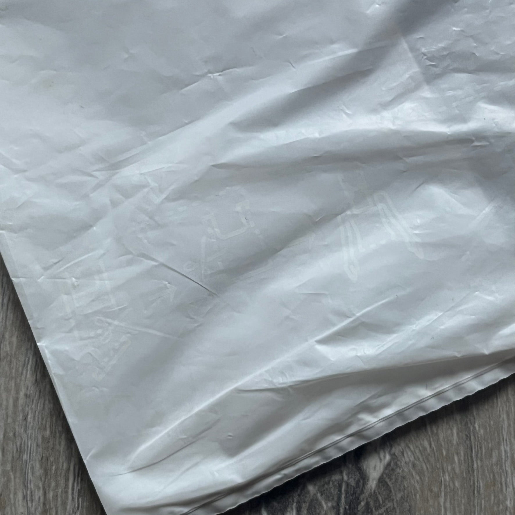 Clear/white plastic bag from the Maison Margiela x H&amp;M collaboration, designed with a cut-off bottom that allows it to be worn as a top or tank. Features big Maison Margiela x H&amp;M logos printed on the front, visible through the semi-transparent material.
