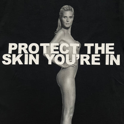 Marc Jacobs 2010s “Protect The Skin You’re In” Heidi Klum T-shirt is a black campaign tee created for skin cancer awareness. The front features an illustrative image of Heidi Klum with “Protect The Skin You’re In” text integrated into the design. The sleeves include references to “In loving memory of Dr Jessie Rubin” and support for NYU Medical Center Cancer Institute. The back displays a large “Thank You” message listing contributors to the campaign.
