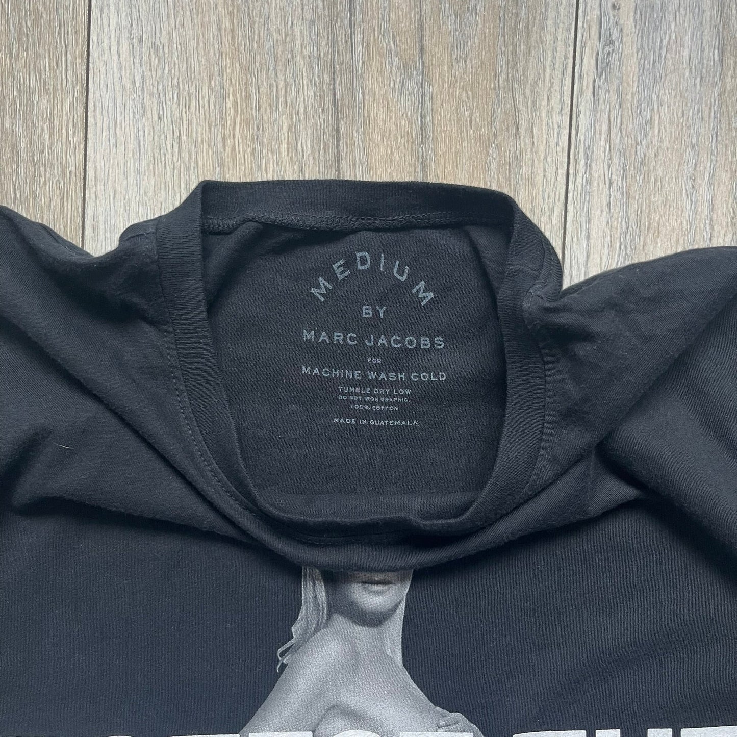 Marc Jacobs 2010s “Protect The Skin You’re In” Heidi Klum T-shirt is a black campaign tee created for skin cancer awareness. The front features an illustrative image of Heidi Klum with “Protect The Skin You’re In” text integrated into the design. The sleeves include references to “In loving memory of Dr Jessie Rubin” and support for NYU Medical Center Cancer Institute. The back displays a large “Thank You” message listing contributors to the campaign.