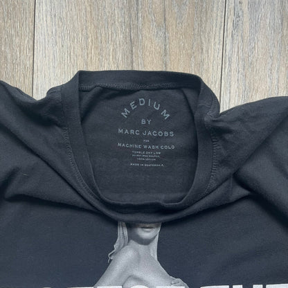 Marc Jacobs 2010s “Protect The Skin You’re In” Heidi Klum T-shirt is a black campaign tee created for skin cancer awareness. The front features an illustrative image of Heidi Klum with “Protect The Skin You’re In” text integrated into the design. The sleeves include references to “In loving memory of Dr Jessie Rubin” and support for NYU Medical Center Cancer Institute. The back displays a large “Thank You” message listing contributors to the campaign.