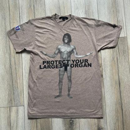 Marc Jacobs 2010s “Protect Your Largest Organ” Chico Clark T-shirt is a light brown awareness campaign tee created to support skin cancer prevention initiatives. The front features an artistic illustration of Chico Clark with accompanying “Protect Your Largest Organ” text. The sleeves include printed details referencing the collaboration and support for NYU School of Medicine. The back displays a large “Thank You” message with credits to contributors involved in the campaign.