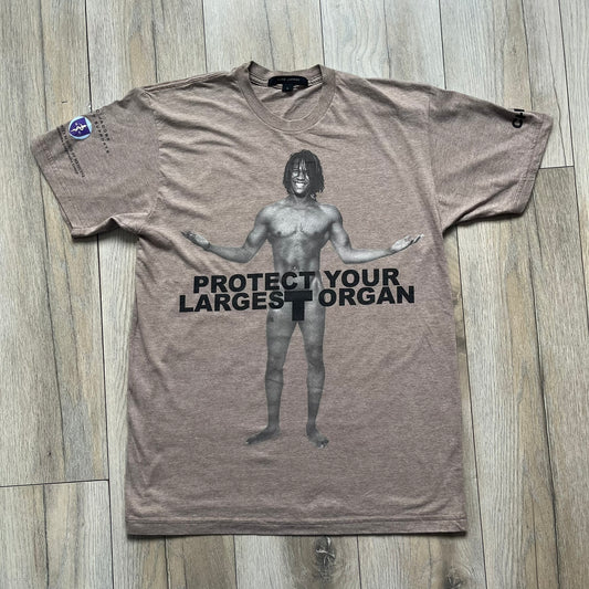 Marc Jacobs 2010s “Protect Your Largest Organ” Chico Clark T-shirt is a light brown awareness campaign tee created to support skin cancer prevention initiatives. The front features an artistic illustration of Chico Clark with accompanying “Protect Your Largest Organ” text. The sleeves include printed details referencing the collaboration and support for NYU School of Medicine. The back displays a large “Thank You” message with credits to contributors involved in the campaign.