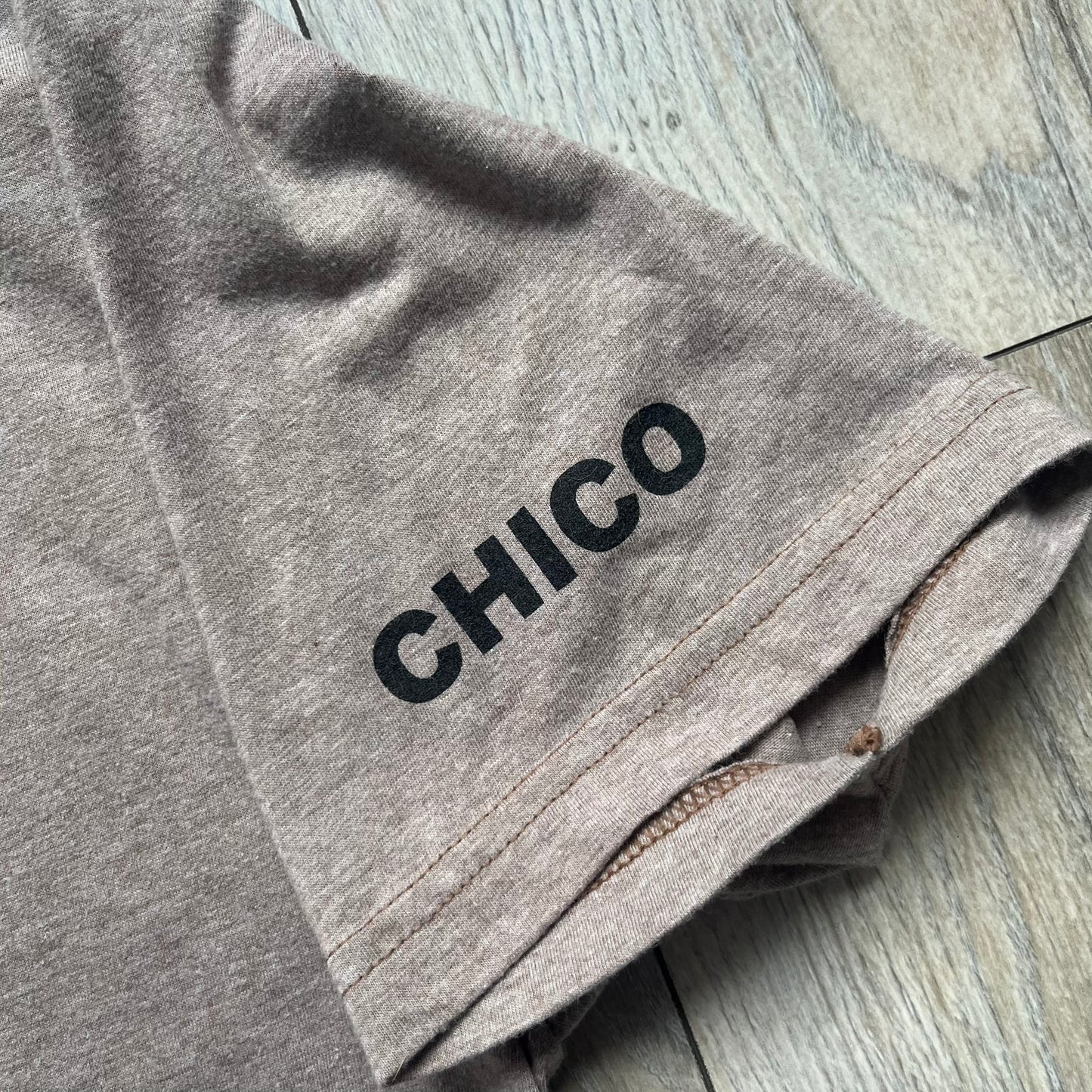 Marc Jacobs 2010s “Protect Your Largest Organ” Chico Clark T-shirt is a light brown awareness campaign tee created to support skin cancer prevention initiatives. The front features an artistic illustration of Chico Clark with accompanying “Protect Your Largest Organ” text. The sleeves include printed details referencing the collaboration and support for NYU School of Medicine. The back displays a large “Thank You” message with credits to contributors involved in the campaign.