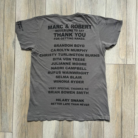 Marc Jacobs 2010s Robert Duffy Skin Cancer Awareness T-shirt is a gray campaign tee created to support skin cancer awareness. The front features an illustrative composition of Robert Duffy with Marc Jacobs included in the design. The sleeves contain printed text referencing “In loving memory of Dr Jessie Rubin” and support for NYU School of Medicine. The back includes a large “Thank You” message listing contributors involved in the campaign.
