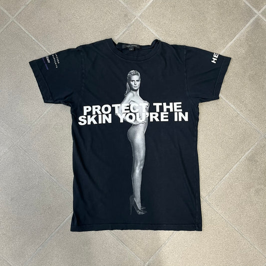 Marc Jacobs 2010s “Protect The Skin You’re In” Heidi Klum T-shirt is a black campaign tee created for skin cancer awareness. The front features an illustrative image of Heidi Klum with “Protect The Skin You’re In” text integrated into the design. The sleeves include "Heidi” and support for NYU Medical Center Cancer Institute. The back displays a large “Thank You” message listing contributors to the campaign.
