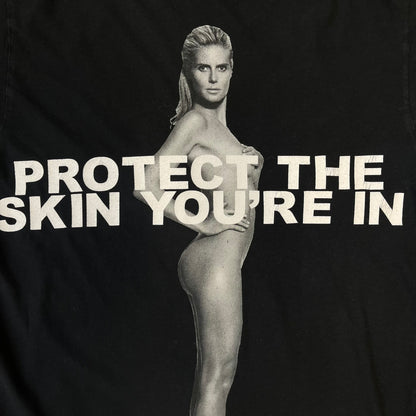 Marc Jacobs 2010s “Protect The Skin You’re In” Heidi Klum T-shirt is a black campaign tee created for skin cancer awareness. The front features an illustrative image of Heidi Klum with “Protect The Skin You’re In” text integrated into the design. The sleeves include "Heidi” and support for NYU Medical Center Cancer Institute. The back displays a large “Thank You” message listing contributors to the campaign.