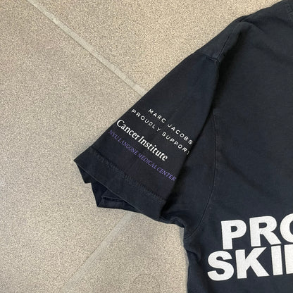 Marc Jacobs 2010s “Protect The Skin You’re In” Heidi Klum T-shirt is a black campaign tee created for skin cancer awareness. The front features an illustrative image of Heidi Klum with “Protect The Skin You’re In” text integrated into the design. The sleeves include "Heidi” and support for NYU Medical Center Cancer Institute. The back displays a large “Thank You” message listing contributors to the campaign.