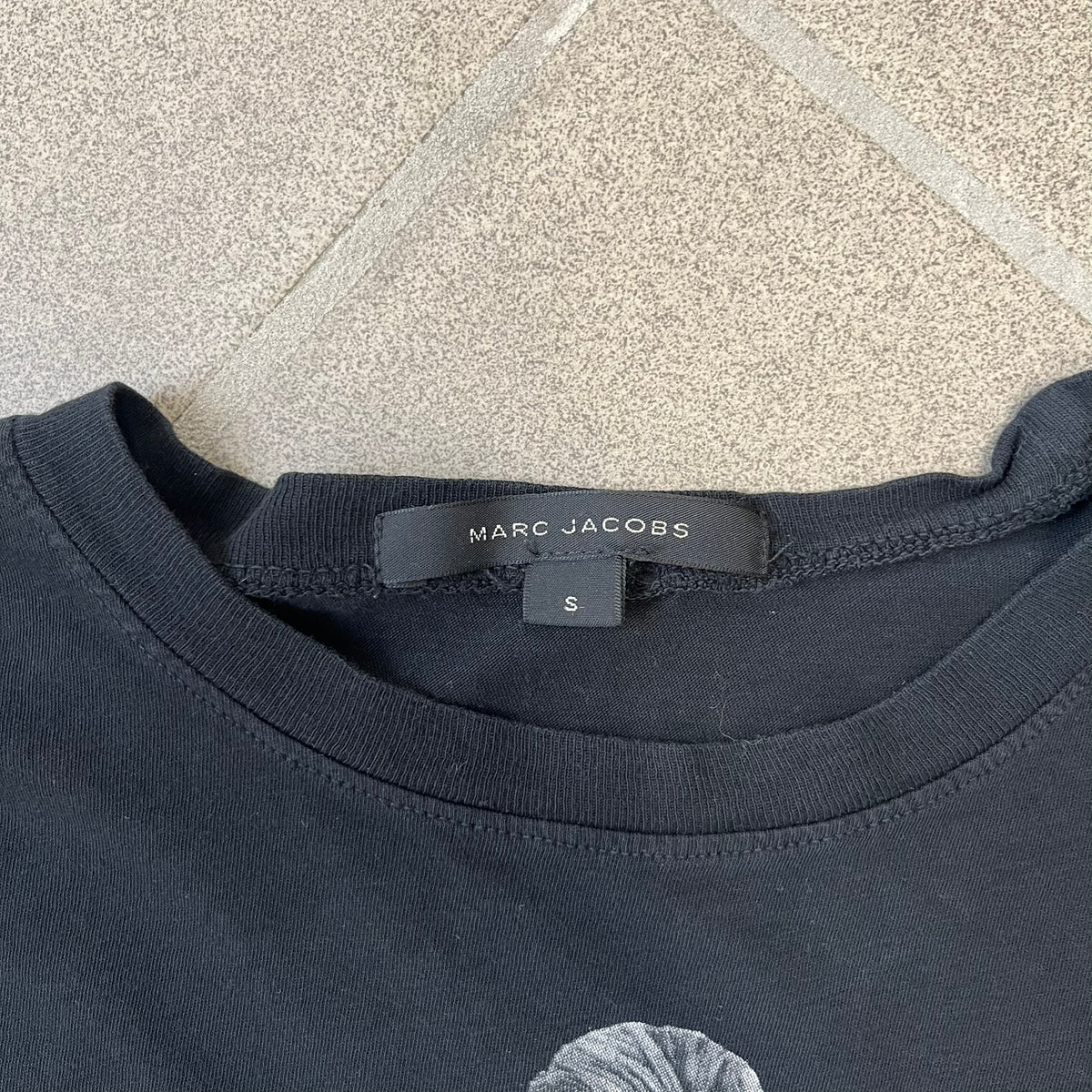 Marc Jacobs 2010s “Protect The Skin You’re In” Heidi Klum T-shirt is a black campaign tee created for skin cancer awareness. The front features an illustrative image of Heidi Klum with “Protect The Skin You’re In” text integrated into the design. The sleeves include "Heidi” and support for NYU Medical Center Cancer Institute. The back displays a large “Thank You” message listing contributors to the campaign.