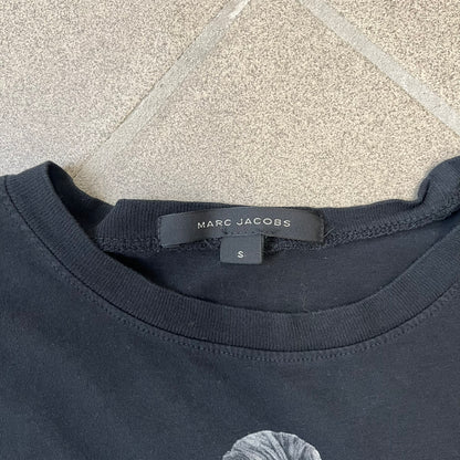 Marc Jacobs 2010s “Protect The Skin You’re In” Heidi Klum T-shirt is a black campaign tee created for skin cancer awareness. The front features an illustrative image of Heidi Klum with “Protect The Skin You’re In” text integrated into the design. The sleeves include "Heidi” and support for NYU Medical Center Cancer Institute. The back displays a large “Thank You” message listing contributors to the campaign.