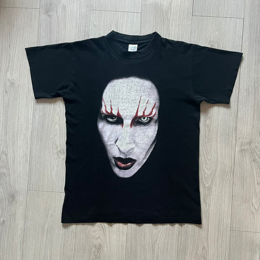 Marilyn Manson Holy Wood Face Tee from 2000, made on a black BG blank. Features a large front graphic of Manson’s face with signature white makeup, red accents, and eye contact. The back includes red Marilyn Manson text with a small 2000 Giant license, great piece from the Holy Wood era.