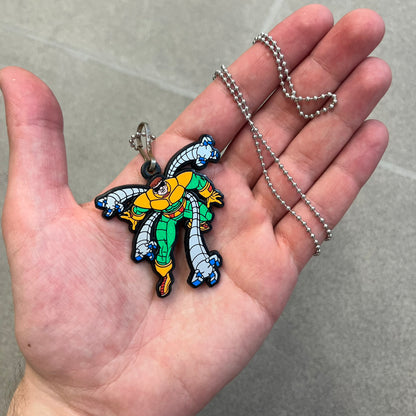 Marvel 1995 Doctor Octopus Necklace features a 2D cartoon-style Doctor Octopus pendant with a colorful graphic on the front. The back of the pendant is black and includes 1995 Marvel licensing details. It has a metal loop at the top and comes with a basic steel chain.
