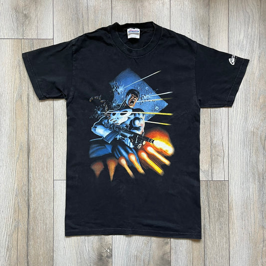 Black Marvel T-shirt from 2002 featuring artwork from The Punisher Limited Series (1985) illustrated by Mike Zeck and Phil Zimelman. The large front graphic shows The Punisher firing a minigun with bullets flying across the scene, based on the original comic poster artwork. Produced on a Hanes Heavyweight blank with a Marvel 2002 sleeve tag and Raphitti branding.