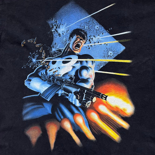 Black Marvel T-shirt from 2002 featuring artwork from The Punisher Limited Series (1985) illustrated by Mike Zeck and Phil Zimelman. The large front graphic shows The Punisher firing a minigun with bullets flying across the scene, based on the original comic poster artwork. Produced on a Hanes Heavyweight blank with a Marvel 2002 sleeve tag and Raphitti branding.