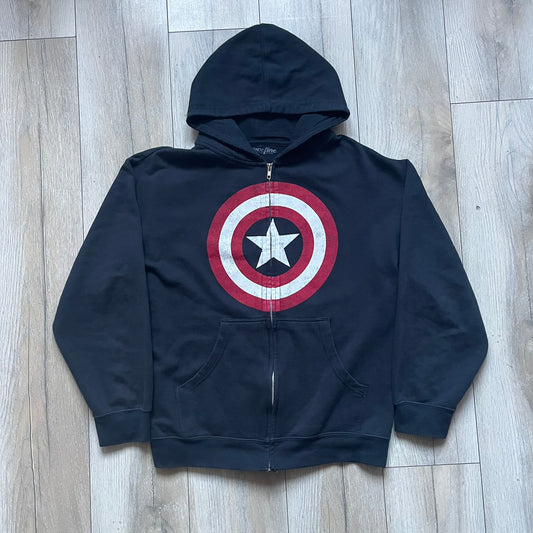 Black hoodie with a large Captain America shield graphic on the front. Made from an 80/20 polyester blend, lightweight. Features metal zipper, front pockets, and WeLoveFine × Marvel neck tag. The shield graphic has an intentional rough texture.