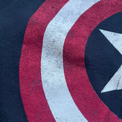 Black hoodie with a large Captain America shield graphic on the front. Made from an 80/20 polyester blend, lightweight. Features metal zipper, front pockets, and WeLoveFine × Marvel neck tag. The shield graphic has an intentional rough texture.