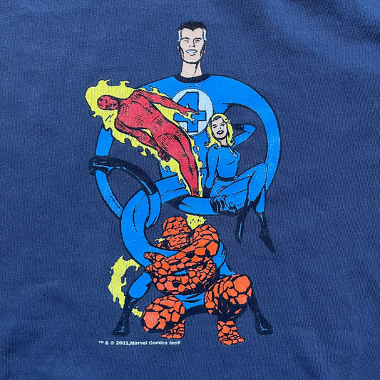 Marvel Fantastic Four 2003 Navy Crewneck is a navy sweatshirt made from 100% cotton with an official Marvel neck tag. The front features a central graphic of the Fantastic Four characters intertwined together, with Reed Richards in a stretched form, Human Torch flying above, Ben Grimm holding Reed, and Sue Storm positioned within the composition. Small white licensing text with the 2003 date appears beneath the graphic.