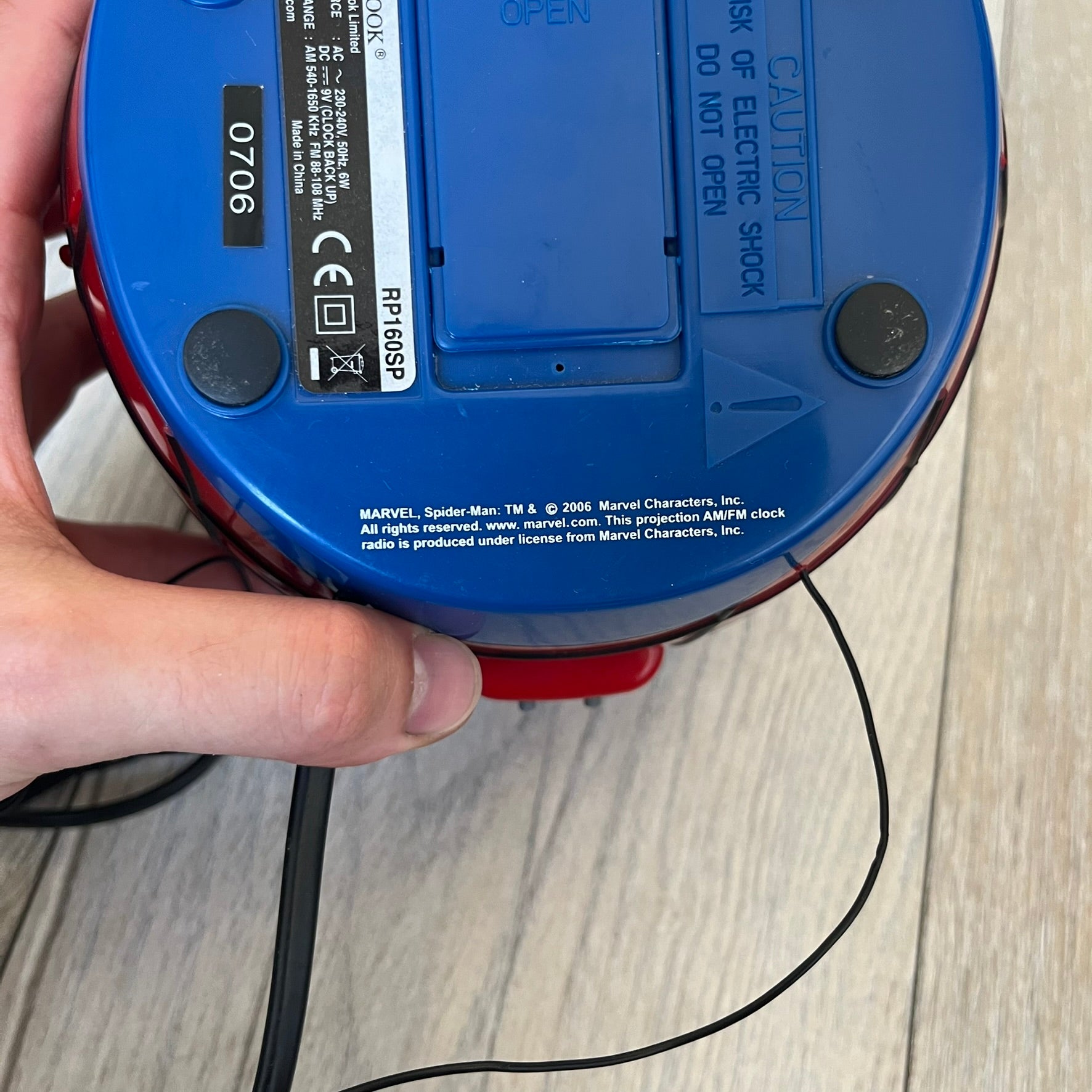 Marvel Spider-Man 2006 AM/FM Alarm Clock Radio is a digital alarm clock shaped like Spider-Man’s head with a multicolor design. It features AM/FM radio functionality and a built-in red projection display that projects the time onto a nearby surface. The clock operates using a standard 110V two-prong power connection or a 9V backup battery. All functions are fully working.
