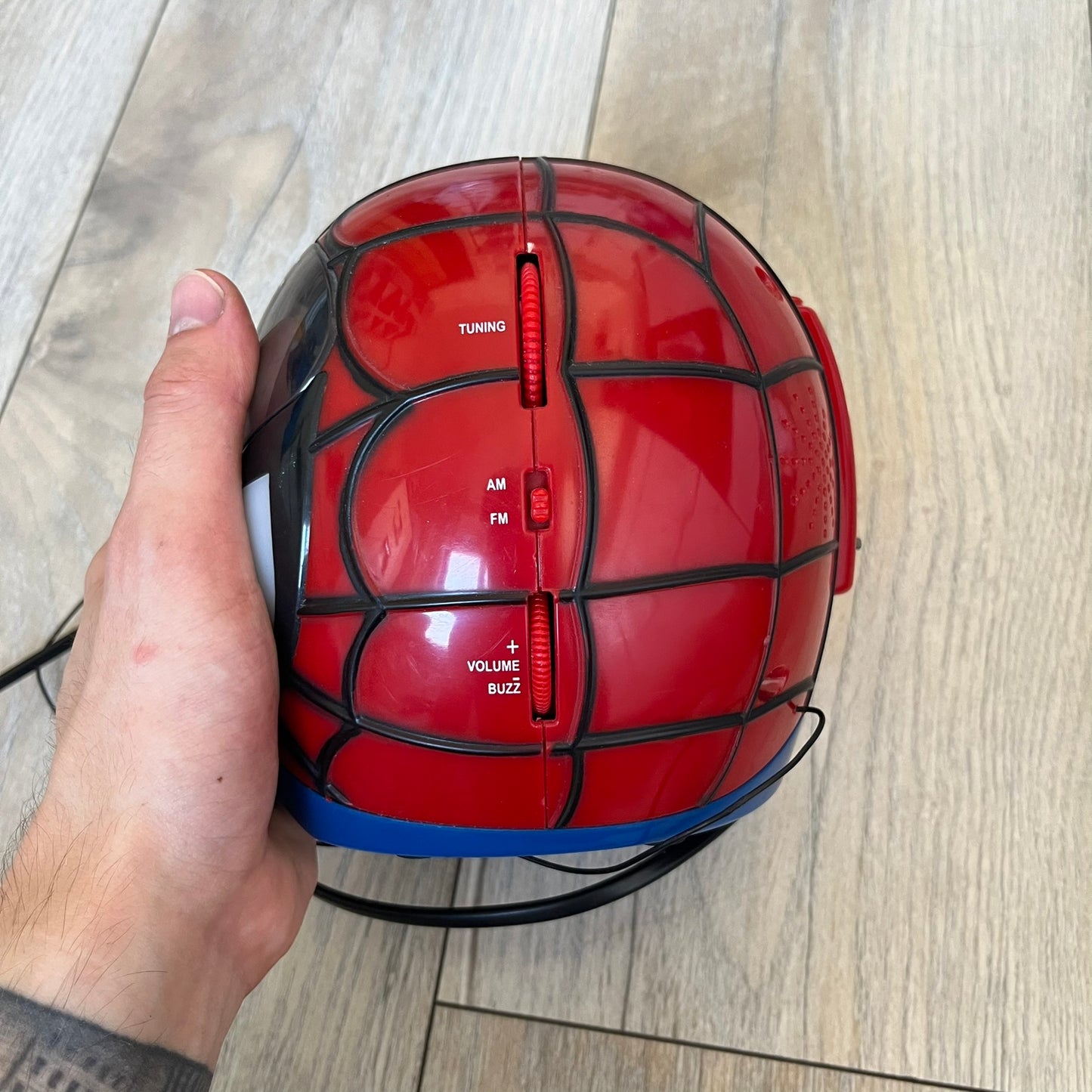 Marvel Spider-Man 2006 AM/FM Alarm Clock Radio is a digital alarm clock shaped like Spider-Man’s head with a multicolor design. It features AM/FM radio functionality and a built-in red projection display that projects the time onto a nearby surface. The clock operates using a standard 110V two-prong power connection or a 9V backup battery. All functions are fully working.
