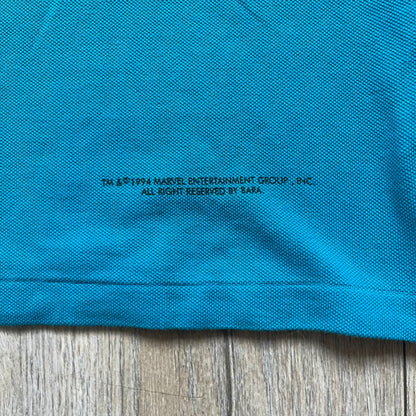 Marvel Comics Spider-Man 1994 Blue Embroidered Polo is a blue polo shirt featuring embroidered Spider-Man branding. The left chest displays an embroidered Spider-Man graphic, while the sleeve includes yellow “Spider-Man” text embroidery. The lower front is finished with small black “1994” text, and the shirt includes a large Marvel Comics neck tag.