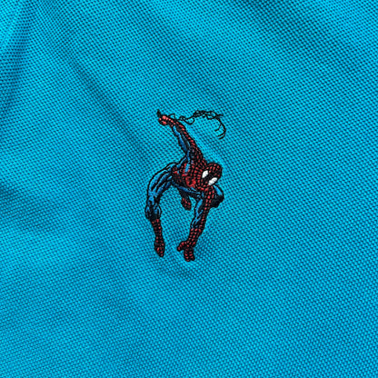 Marvel Comics Spider-Man 1994 Blue Embroidered Polo is a blue polo shirt featuring embroidered Spider-Man branding. The left chest displays an embroidered Spider-Man graphic, while the sleeve includes yellow “Spider-Man” text embroidery. The lower front is finished with small black “1994” text, and the shirt includes a large Marvel Comics neck tag.
