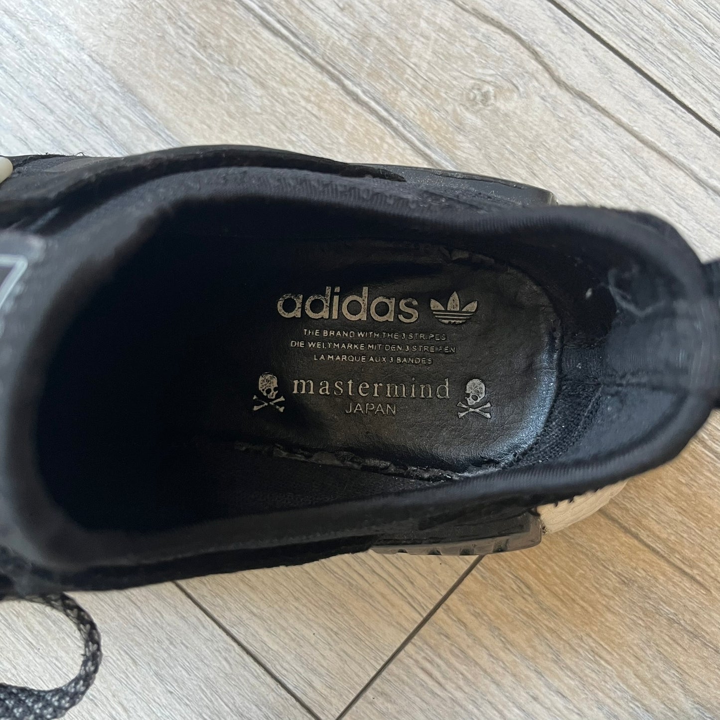 Mastermind x adidas NMD XR1 “Mastermind” Sneakers BA9726 are a 2016 collaboration between adidas and Mastermind Japan, the Japanese label founded by Masaaki Homma. The sneaker features a Core Black/Core Black/White colorway with a polyester mesh upper, rubber sole, and adidas Boost midsole. Mastermind’s signature skull and crossbones logo appears on the leather cage and tongue, while the pair includes black laces and follows the NMD XR1 silhouette released on September 20, 2016 under style code BA9726