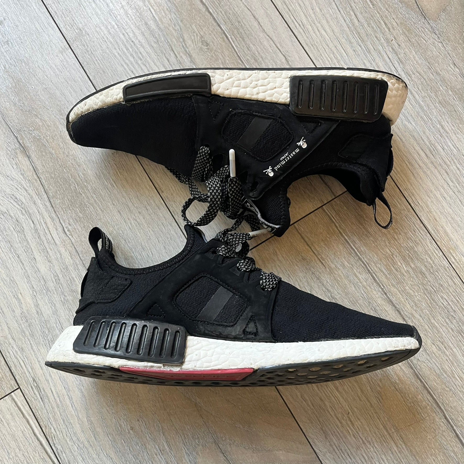 Mastermind x adidas NMD XR1 “Mastermind” Sneakers BA9726 are a 2016 collaboration between adidas and Mastermind Japan, the Japanese label founded by Masaaki Homma. The sneaker features a Core Black/Core Black/White colorway with a polyester mesh upper, rubber sole, and adidas Boost midsole. Mastermind’s signature skull and crossbones logo appears on the leather cage and tongue, while the pair includes black laces and follows the NMD XR1 silhouette released on September 20, 2016 under style code BA9726