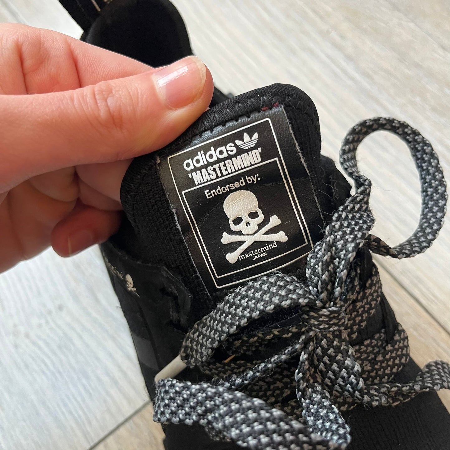 Mastermind x adidas NMD XR1 “Mastermind” Sneakers BA9726 are a 2016 collaboration between adidas and Mastermind Japan, the Japanese label founded by Masaaki Homma. The sneaker features a Core Black/Core Black/White colorway with a polyester mesh upper, rubber sole, and adidas Boost midsole. Mastermind’s signature skull and crossbones logo appears on the leather cage and tongue, while the pair includes black laces and follows the NMD XR1 silhouette released on September 20, 2016 under style code BA9726