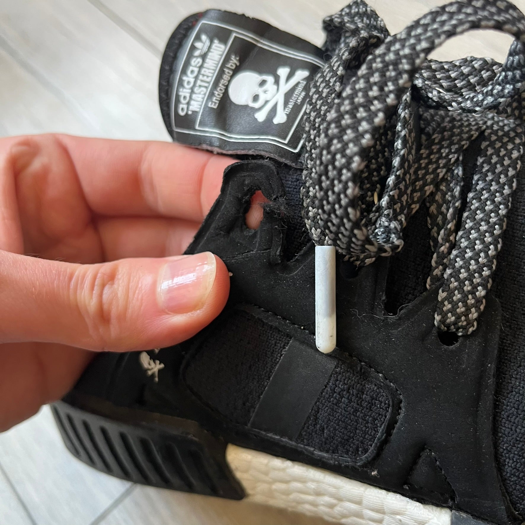 Mastermind x adidas NMD XR1 “Mastermind” Sneakers BA9726 are a 2016 collaboration between adidas and Mastermind Japan, the Japanese label founded by Masaaki Homma. The sneaker features a Core Black/Core Black/White colorway with a polyester mesh upper, rubber sole, and adidas Boost midsole. Mastermind’s signature skull and crossbones logo appears on the leather cage and tongue, while the pair includes black laces and follows the NMD XR1 silhouette released on September 20, 2016 under style code BA9726