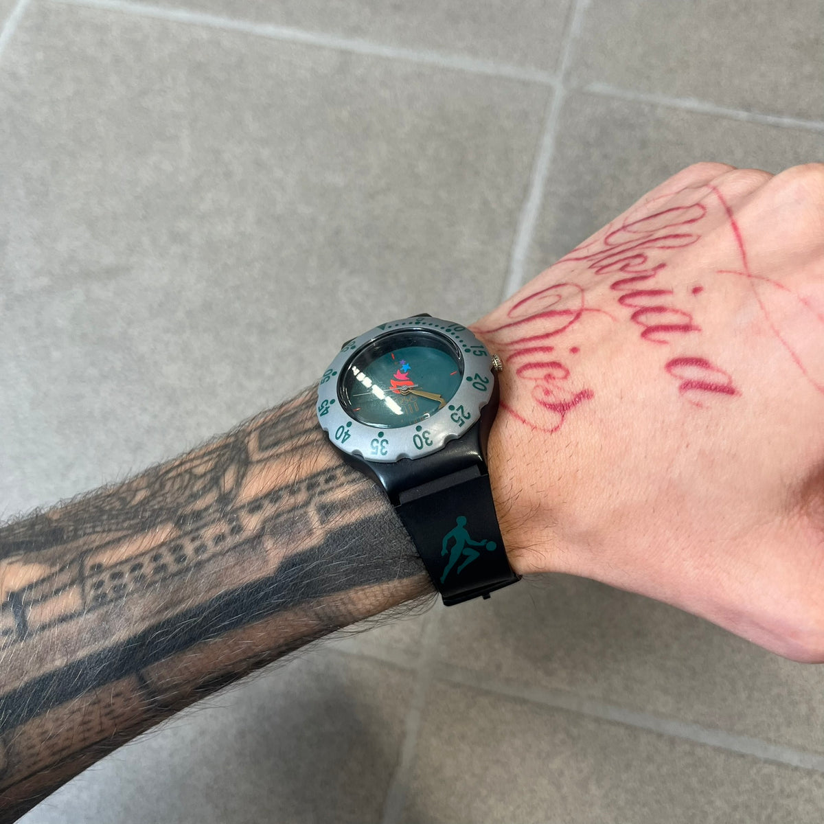 McDonald's 1996 Atlanta Olympics Analog Watch features a black strap decorated with green sports-themed figures and a silver and grey case. The green dial has the Atlanta 1996 Olympic Games logo at the center. A vintage McDonald's promotional watch from the 1996 Atlanta Olympics.
