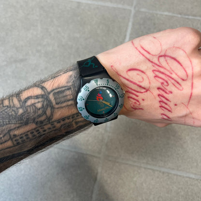McDonald's 1996 Atlanta Olympics Analog Watch features a black strap decorated with green sports-themed figures and a silver and grey case. The green dial has the Atlanta 1996 Olympic Games logo at the center. A vintage McDonald's promotional watch from the 1996 Atlanta Olympics.

