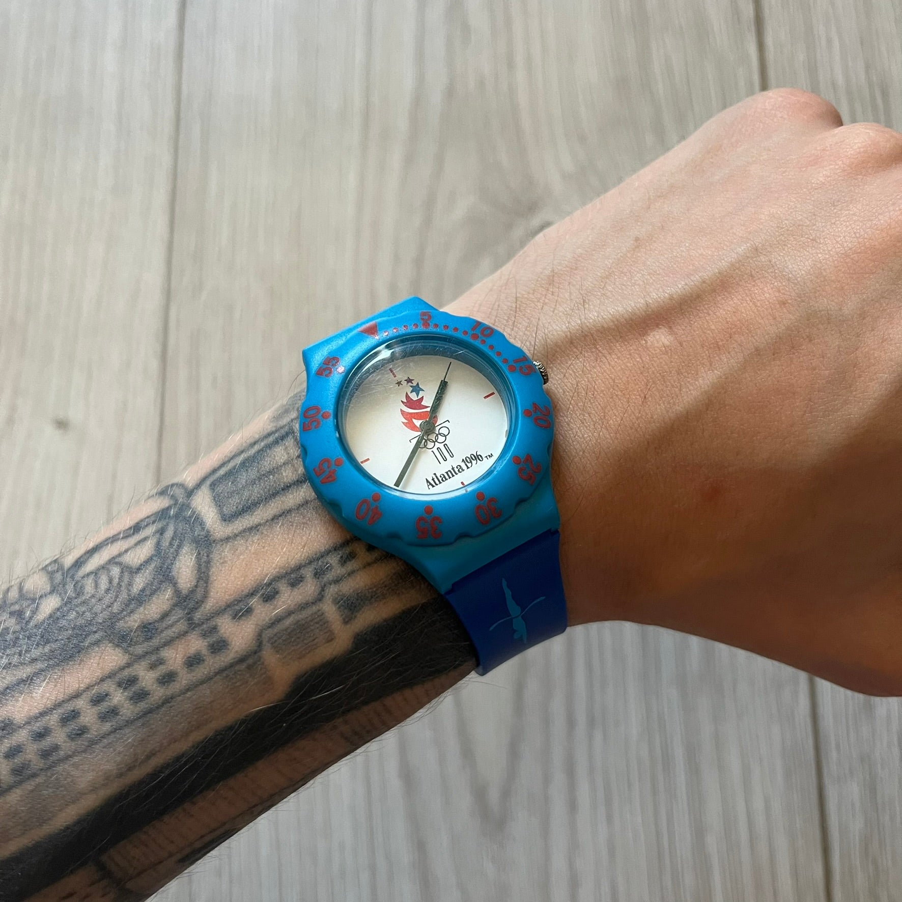 McDonald’s Atlanta 1996 Olympics analog watch with a dark blue strap featuring light blue sport-themed motifs. The dial is white with blue and red accents, showcasing the official Atlanta 1996 logo. A nostalgic collectible celebrating the iconic Olympic collaboration.